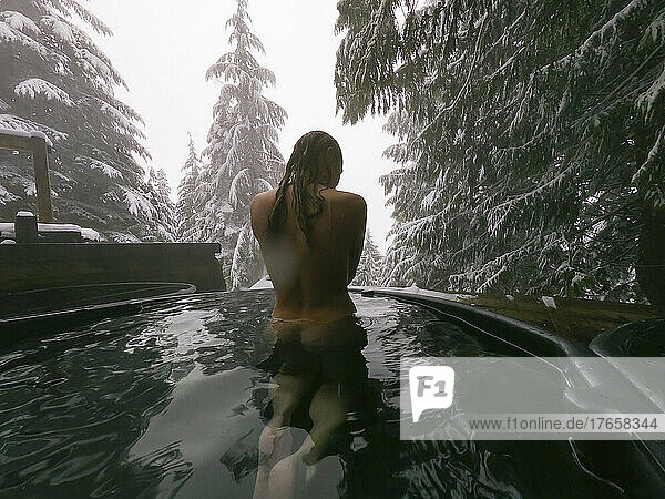 Naked female soaking in a natural hot spring in the winter