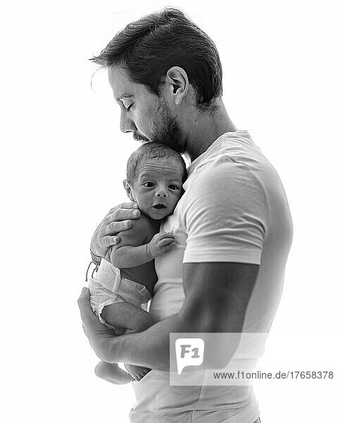 Father with his new born in a back-lit scene in black & white