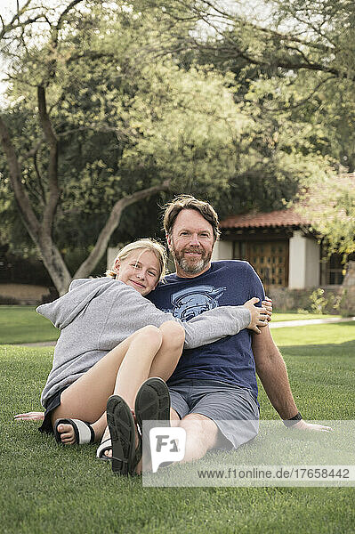 Father and Teenage Girl Embracing on a Grassy Lawn in Arizona