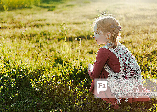 young girl sitting in a green field
