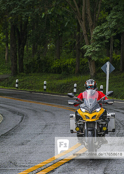 senior biker riding on wet road in north Thailand