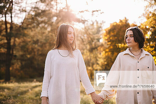 Lesbian couple holding hands while standing in park during autumn