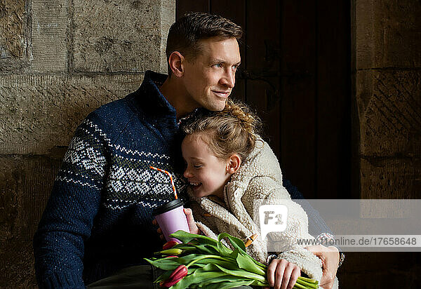 father cuddling his smiling daughter on a hot chocolate date