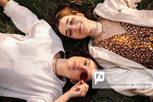 Overhead view of two young women lying on grass