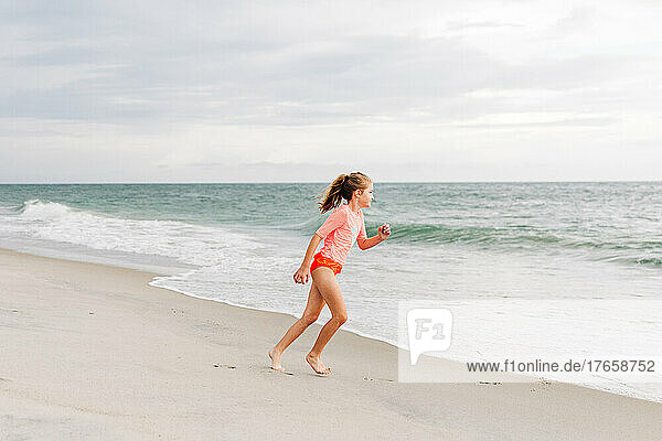 Young girl running in the sand towards the ocean