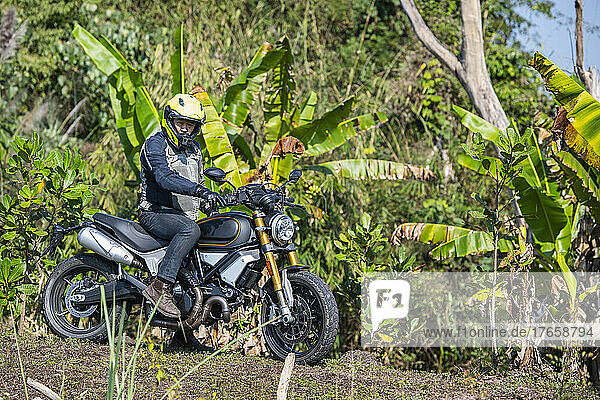 Man with his scrambler type motorcycle on rugged terrain in Thailand