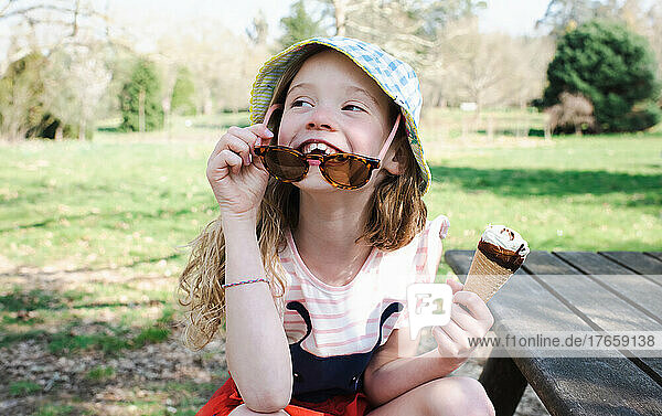 girl happily eating ice cream at the park in summer