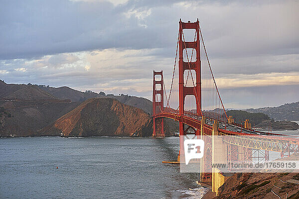 Wide angle view of Golden Gate Bridge against stormy sky at sunset