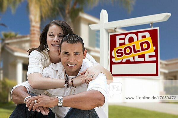 Junge glückliche hispanische junges Paar vor ihrem neuen Haus und verkauft für Verkauf Immobilien Zeichen