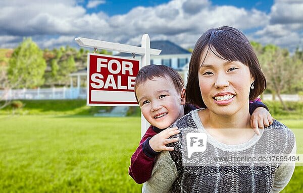Chinese mother and mixed-race child in front of custom house and for sale real estate sign