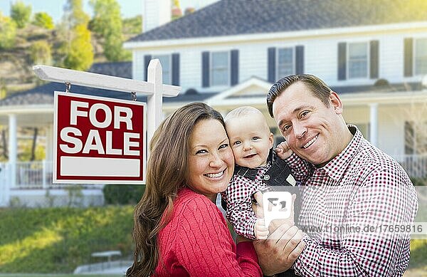 Glückliche junge Familie vor einem Immobilienschild und einem Haus zum Verkauf