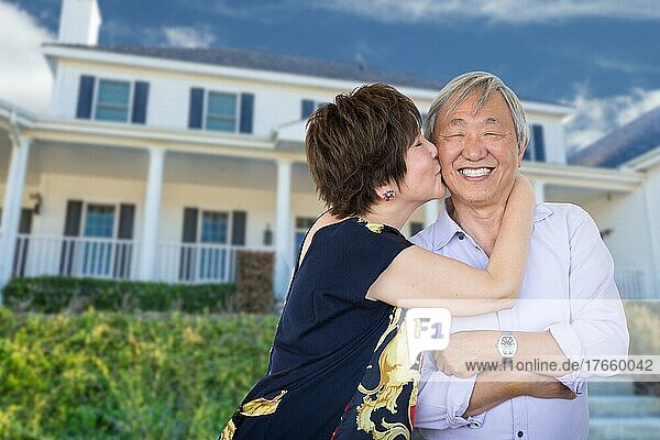 Happy chinese senior adult couple kissing in front of custom house