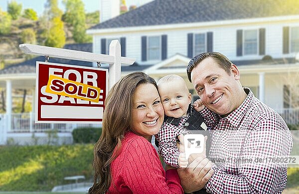 Glückliche junge Familie vor einem Immobilienschild und einem Haus zum Verkauf