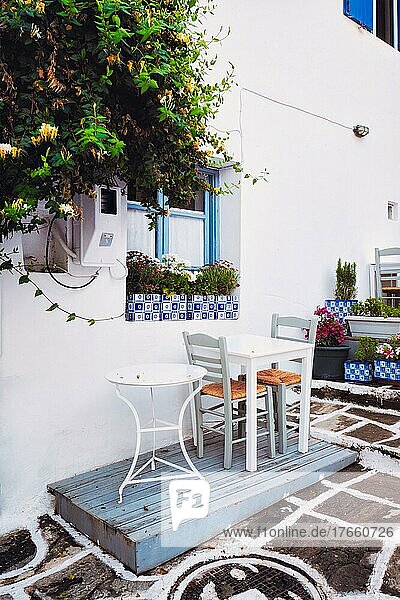 Picturesque narrow street with traditional whitewashed houses with cafe tables of Naousa town in famous tourist attraction Paros island  Greece