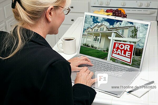 Frau in der Küche mit Laptop zu recherchieren Immobilien. Bildschirm kann leicht für Ihre eigene Nachricht oder Bild verwendet werden