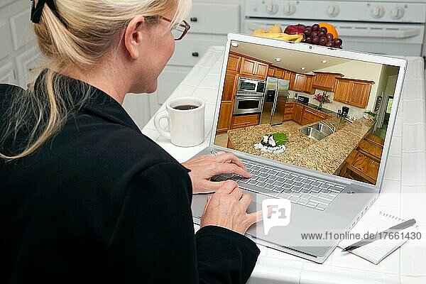 Frau in der Küche  die einen Laptop benutzt  um Heimwerkerideen zu recherchieren. Der Bildschirm kann leicht für eigene Nachrichten oder Bilder verwendet werden. Das Bild auf dem Bildschirm ist auch mein Copyright