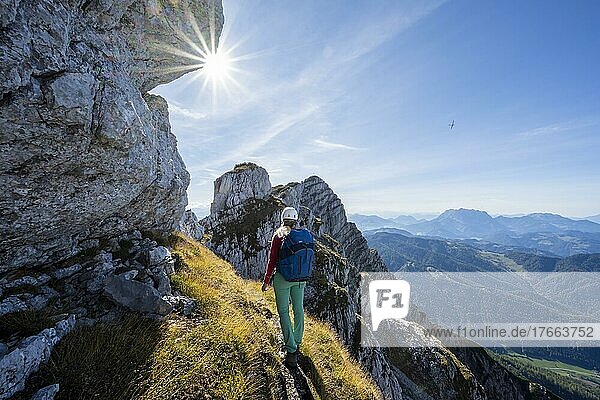 Sonne scheint auf einen Wanderweg mit Wanderin  Blick über Berglandschaft  Nuaracher Höhenweg  Loferer Steinberge  Tirol  Österreich  Europa