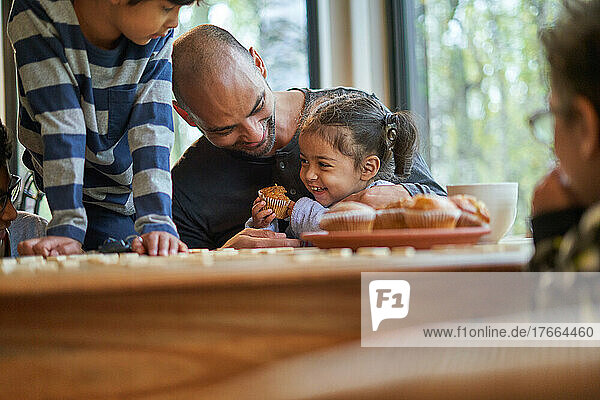 Glücklicher Vater und Tochter essen Muffin am Esstisch