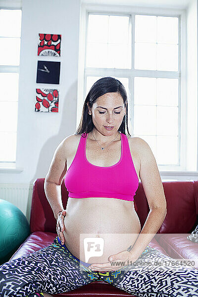 Serene schwangere Frau meditiert und hält Babybauch
