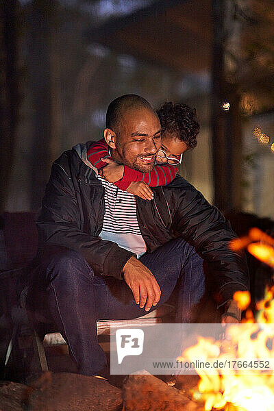 Affectionate son hugging father at campfire