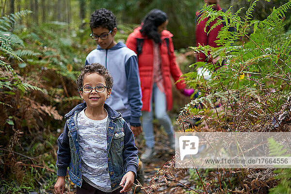 Portrait cute boy hiking with family on trail in woods