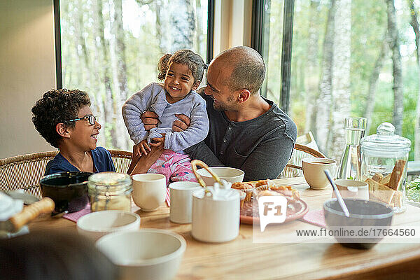 Happy father and kids eating at dining table