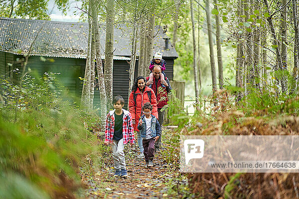 Familie wandert auf einem Pfad im Wald vor einer Hütte