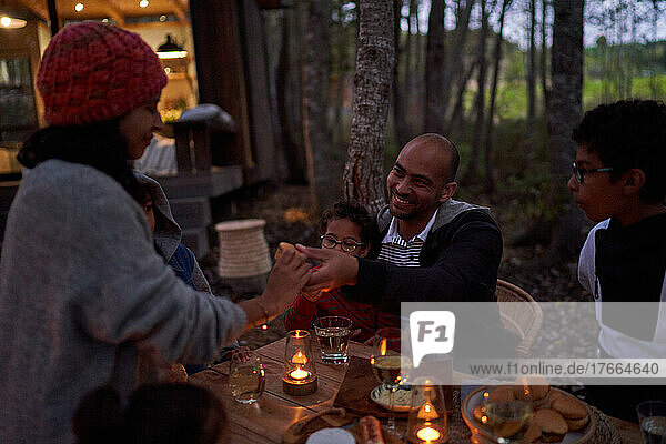 Familie isst bei Kerzenlicht am Tisch vor der Hütte