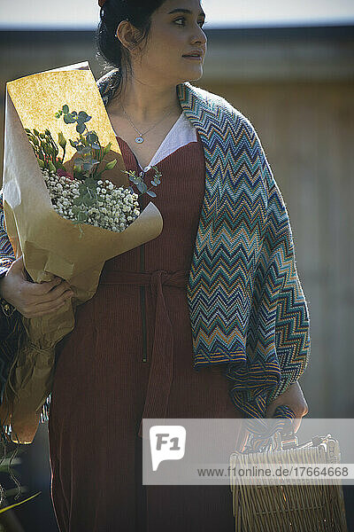 Frau mit Picknickkorb und Blumenstrauß