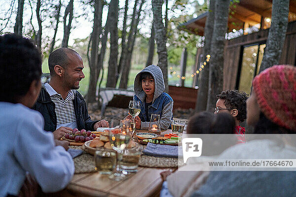 Familie isst am Tisch vor einer Hütte im Wald