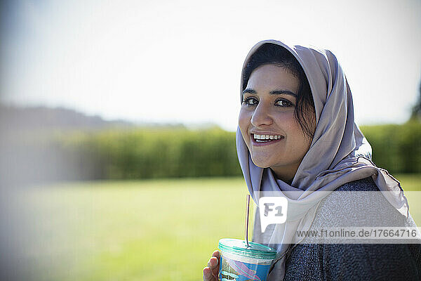Porträt einer glücklichen jungen Muslimin im Hidschab  die Saft trinkt