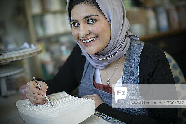 Portrait happy young woman in hijab in art studio