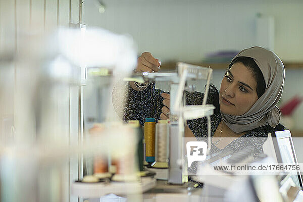 Junge muslimische Näherin bei der Vorbereitung von Garnspulen