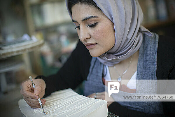 Junge Künstlerin im Hidschab bei der Arbeit im Kunstatelier