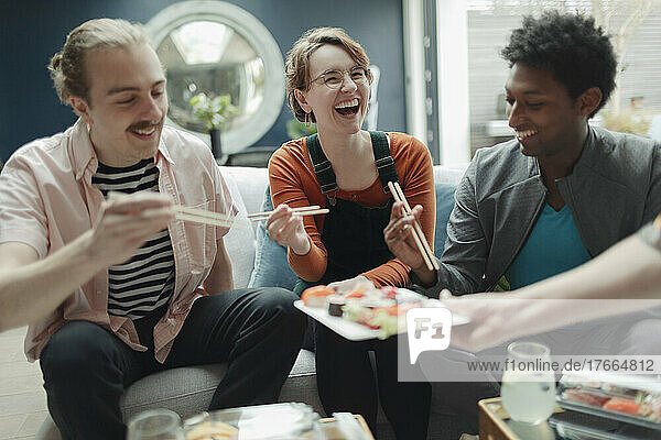 Happy friends sharing sushi in living room