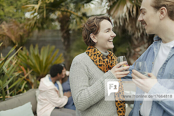 Glückliches junges Paar beim Trinken und Reden auf der Terrasse
