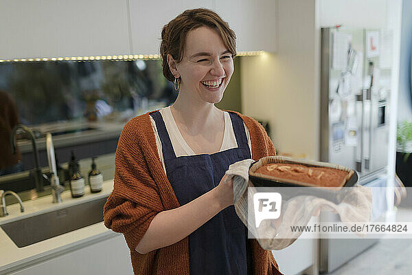 Happy young woman baking loaf cake in kitchen