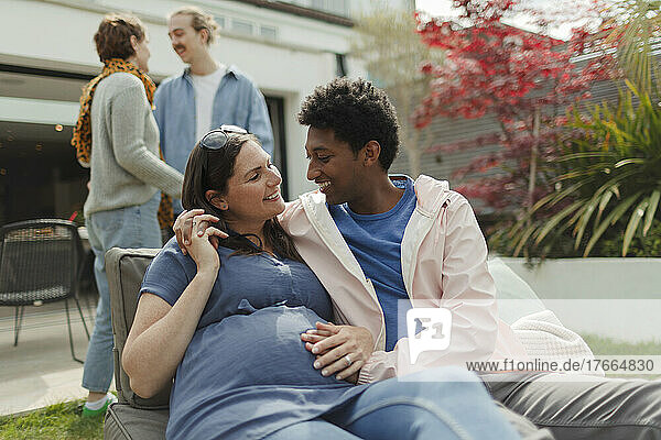 Happy affectionate pregnant couple on sunny patio