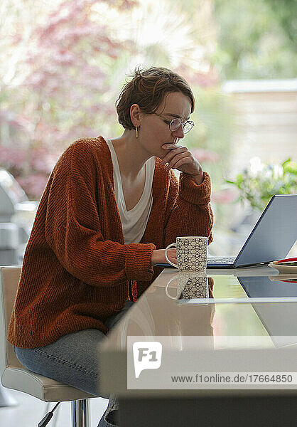 Konzentrierte junge Frau arbeitet von zu Hause aus am Laptop