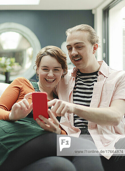Happy young couple with smart phone at home