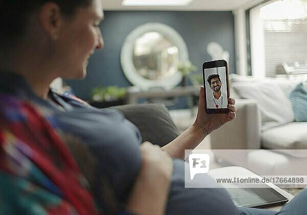 Schwangere Frau im Video-Chat mit Arzt auf Smartphone-Bildschirm