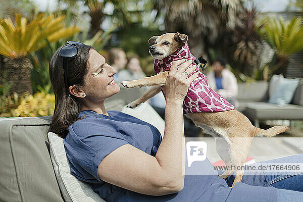 Happy pregnant woman with dog on sunny patio