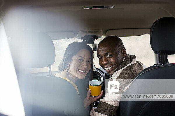 Portrait glückliches Paar trinkt Kaffee im Auto