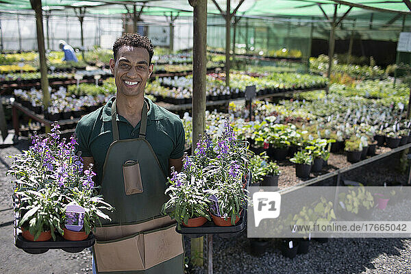 Porträt selbstbewusster männlicher Gartenladenbesitzer mit Topfblumen