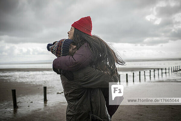 Glückliches  zärtliches Paar  das sich am nassen Winterstrand umarmt