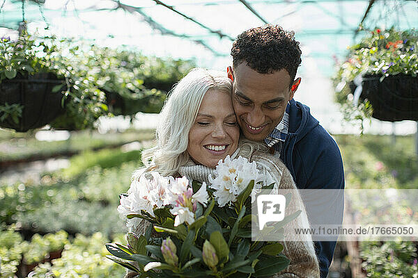 Glückliches  zärtliches Paar  das in einem Gartengeschäft Blumen kauft
