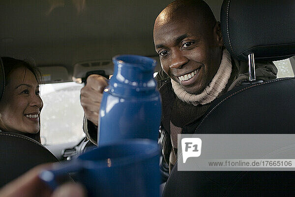 POV Mann gießt Kaffee aus Thermoskanne im Auto