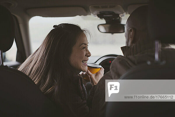 Glückliches Paar trinkt Kaffee im Auto