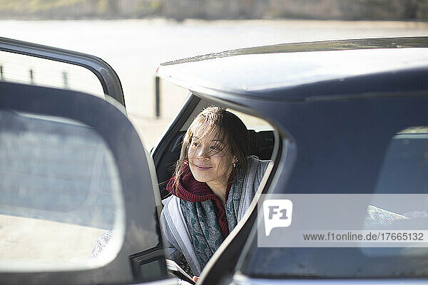 Happy woman relaxing at back of car