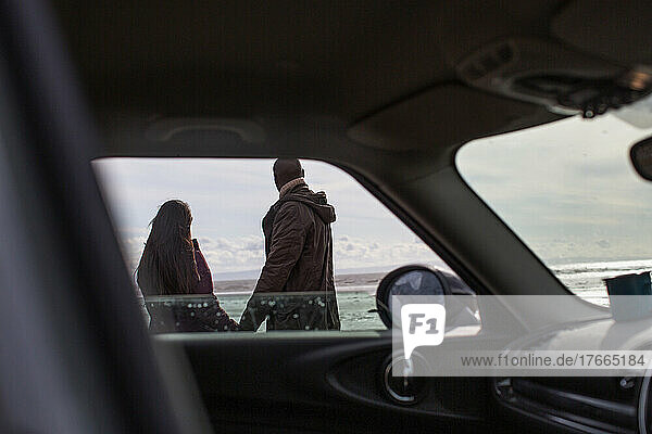 Paar hält Hände außerhalb des Autos am Winterstrand